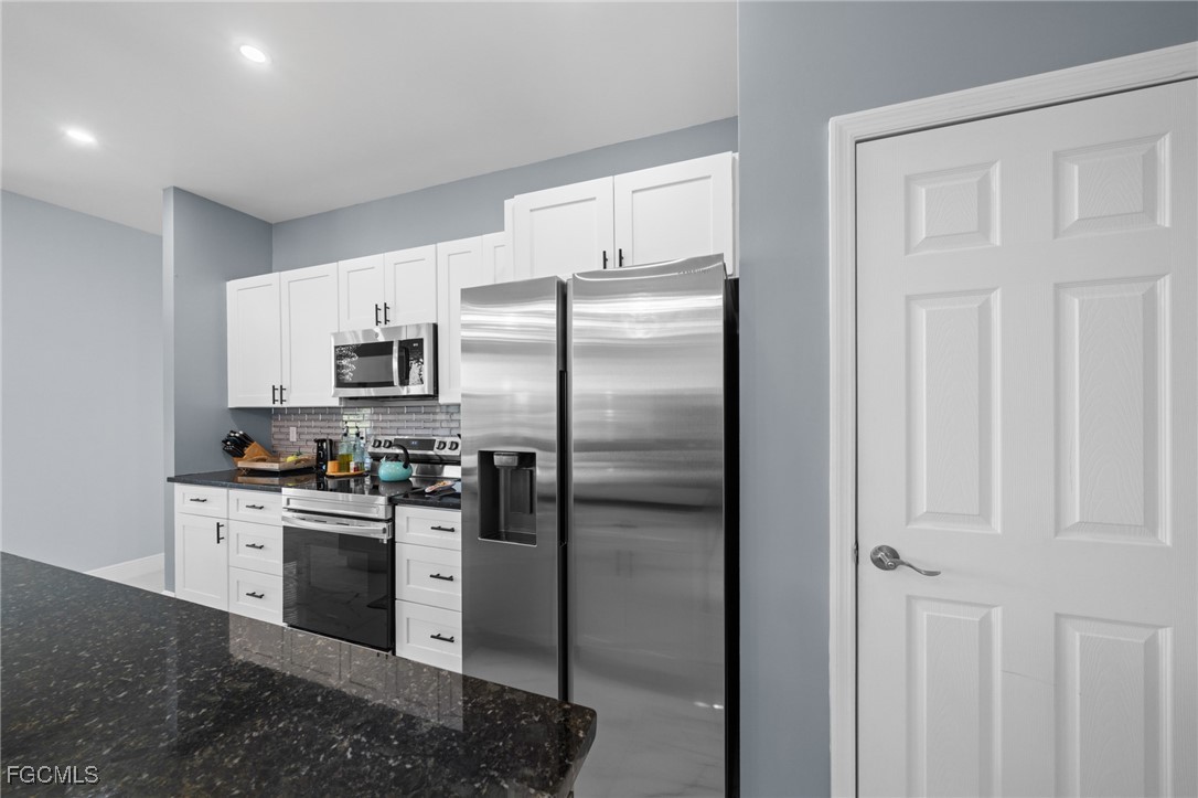 2906 9th Street Southwest Lehigh Acres, FL 33976 - Photo 10 of 30 a kitchen with stainless steel appliances granite countertop a refrigerator a stove and white cabinets