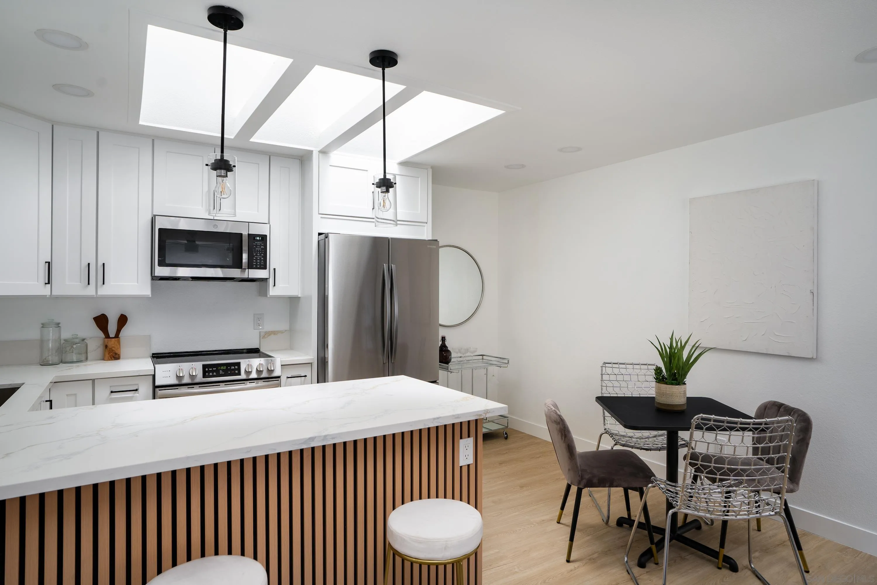 6376 Rancho Mission Road, Unit 402 San Diego, CA 92108 - Photo 4 of 27 a kitchen with stainless steel appliances a table chairs refrigerator and microwave