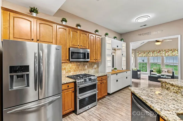 a large kitchen with stainless steel appliances granite countertop a stove and cabinets