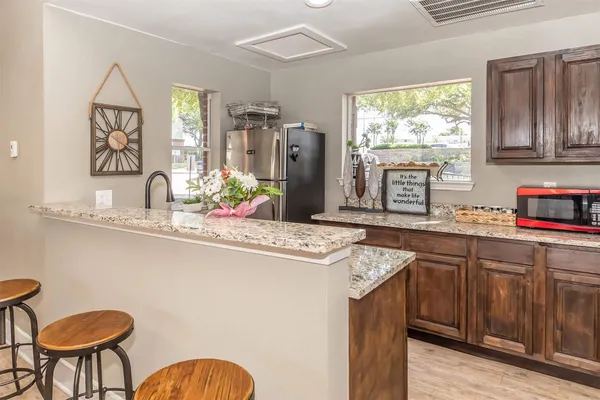 a kitchen with stainless steel appliances granite countertop a sink a stove a refrigerator a dining table and chairs with wooden floor