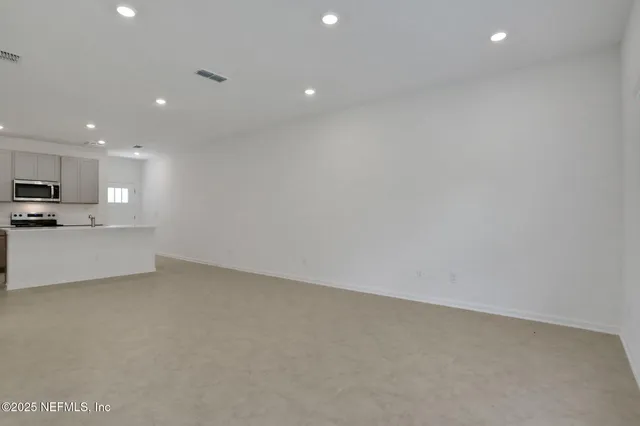 a view of an empty room with kitchen stove and a refrigerator