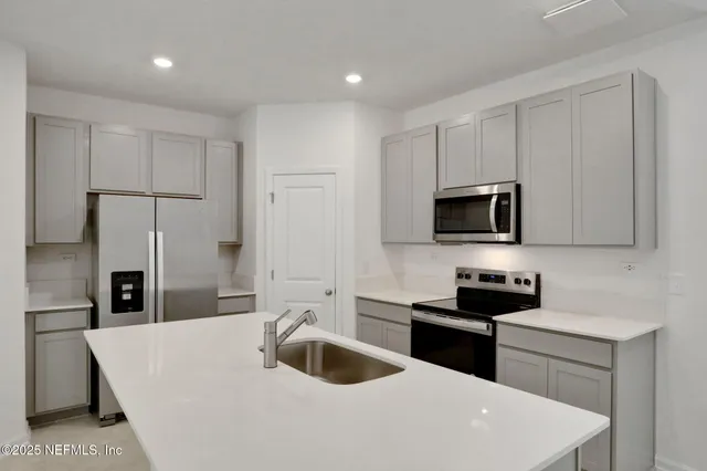 a kitchen with stainless steel appliances a sink a stove a microwave and cabinets