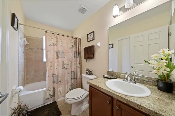 a bathroom with a granite countertop sink toilet a mirror a bathtub and shower