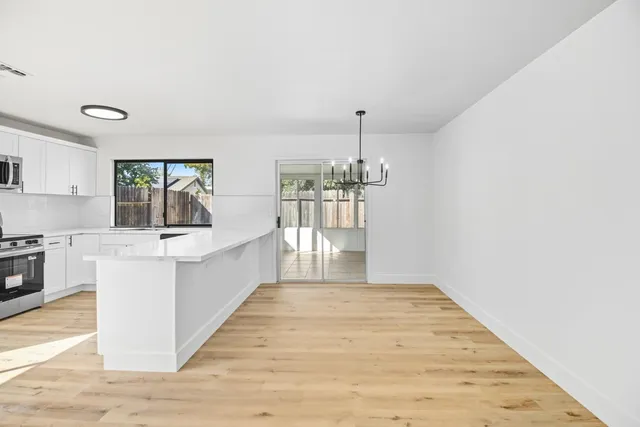 a large white kitchen with kitchen island a stove a sink dishwasher and oven with wooden floor