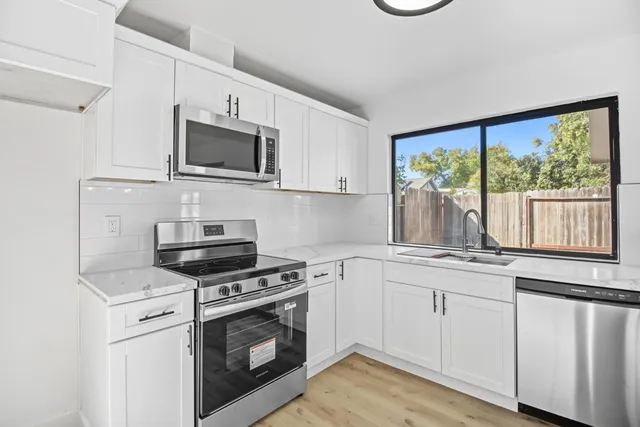 a kitchen with white cabinets stainless steel appliances and sink