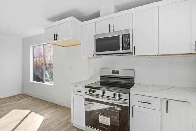 a kitchen with white cabinets stainless steel appliances and wooden floor