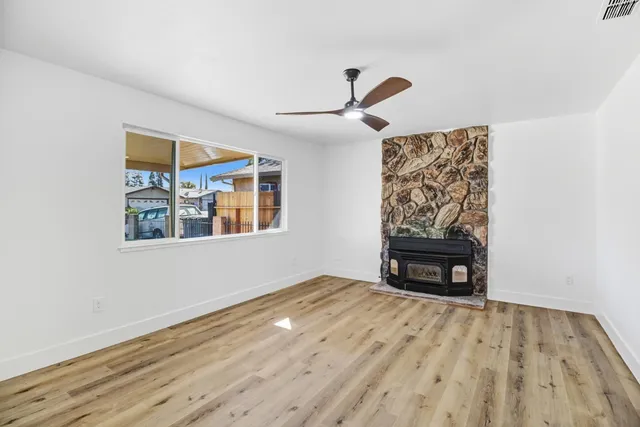 a view of an empty room with window and wooden floor