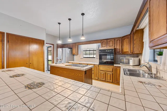 a large kitchen with stainless steel appliances granite countertop a stove a sink and a refrigerator