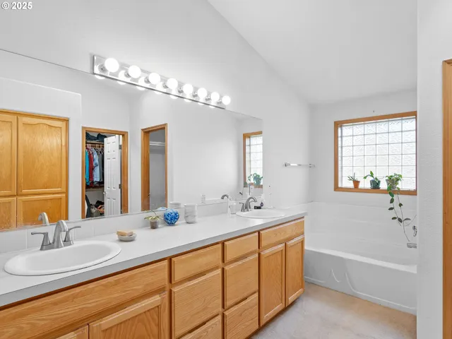 a bathroom with double vanity sinks a large mirror and a bathtub