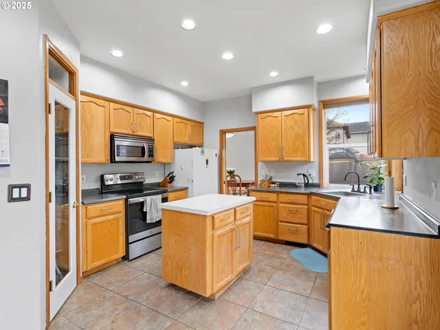 a kitchen with stainless steel appliances granite countertop refrigerator a stove top oven a sink dishwasher and wooden cabinets