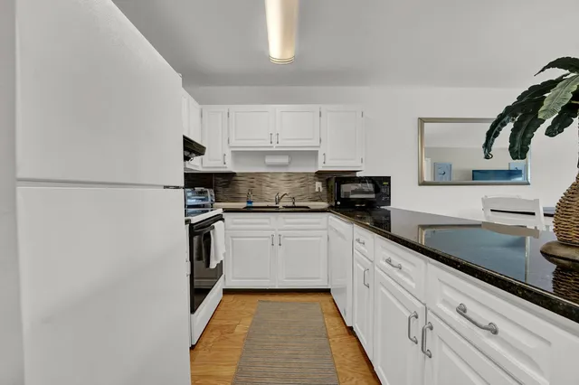 a kitchen with granite countertop white cabinets and white appliances
