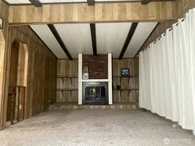 a view of an empty room with wooden floor stairs and a window