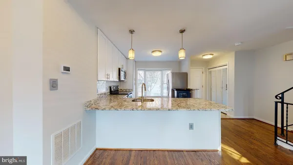 a view of kitchen island a sink wooden floor and living room view
