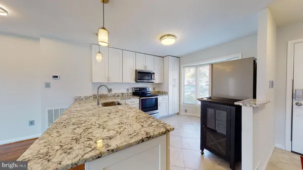 a kitchen with granite countertop kitchen island stainless steel appliances a stove sink microwave and refrigerator