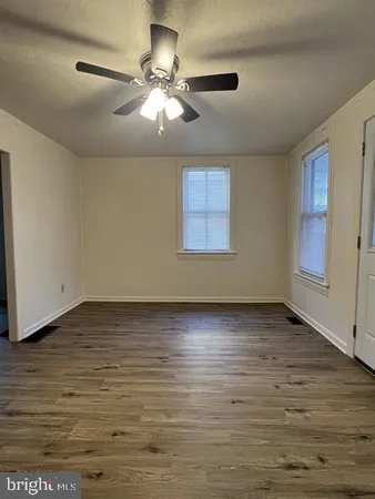 an empty room with wooden floor fan and windows