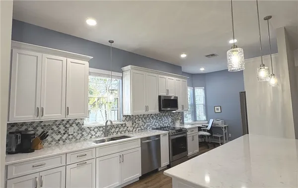 a large kitchen with granite countertop a sink stainless steel appliances and cabinets