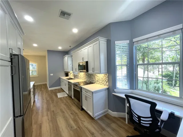 a kitchen with a stove a refrigerator and wooden floor