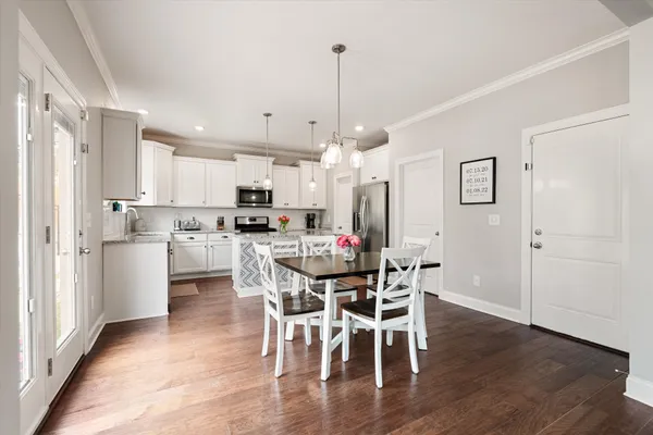 a view of a dining room and livingroom with furniture wooden floor a chandelier