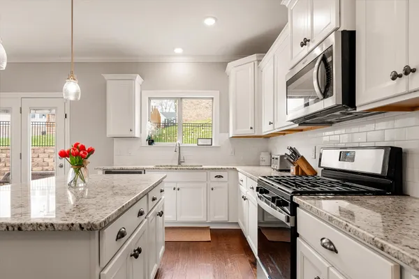 a kitchen with granite countertop a sink stainless steel appliances and cabinets