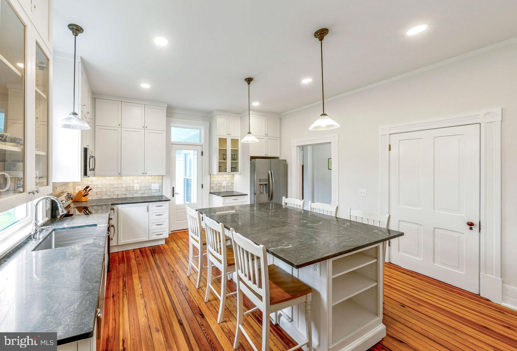 558 Gay Street Washington, VA 22747 - Photo 22 of 52 a kitchen with stainless steel appliances granite countertop a kitchen island a stove a sink a refrigerator white cabinets and couches with wooden floor