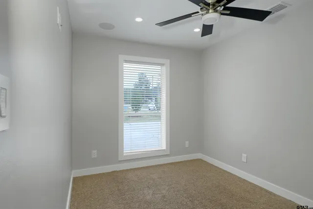 an empty room with a window and a fan