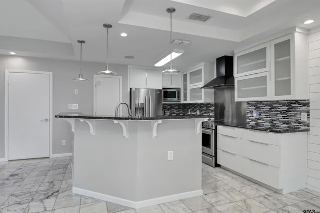 a view of kitchen with stainless steel appliances kitchen island granite countertop a stove a sink a refrigerator and a cabinets
