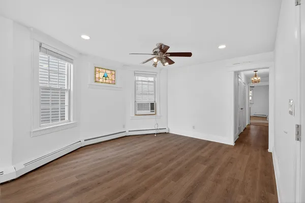 a view of an empty room with a window and wooden floor