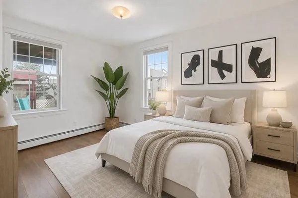 a bedroom with a large bed a potted plant and a window