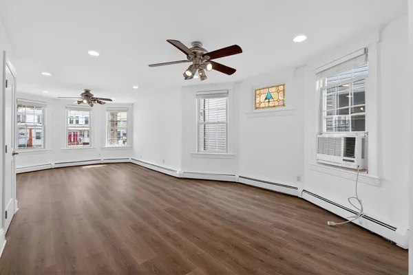 a view of an empty room with a window and wooden floor