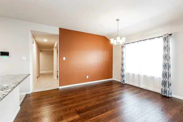 a view of an empty room with window and wooden floor