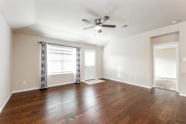 an empty room with wooden floor window and ceiling fan