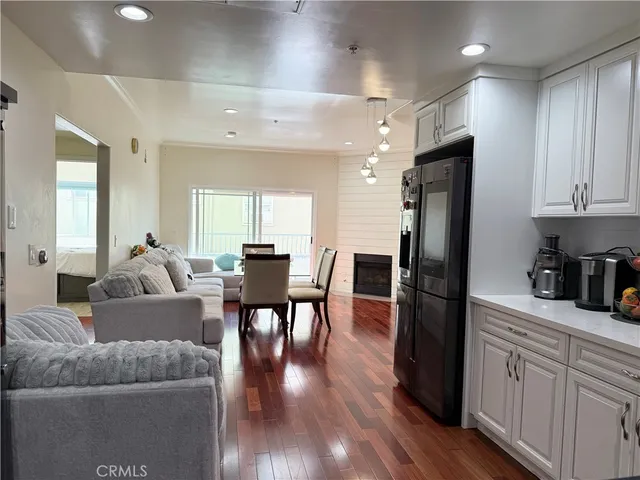 a living room with stainless steel appliances furniture refrigerator and wooden floor