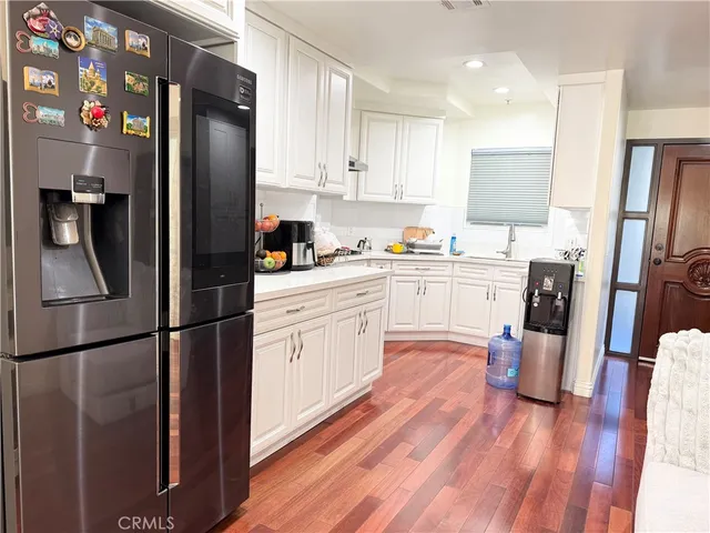 a kitchen with stainless steel appliances a refrigerator sink and wooden floor