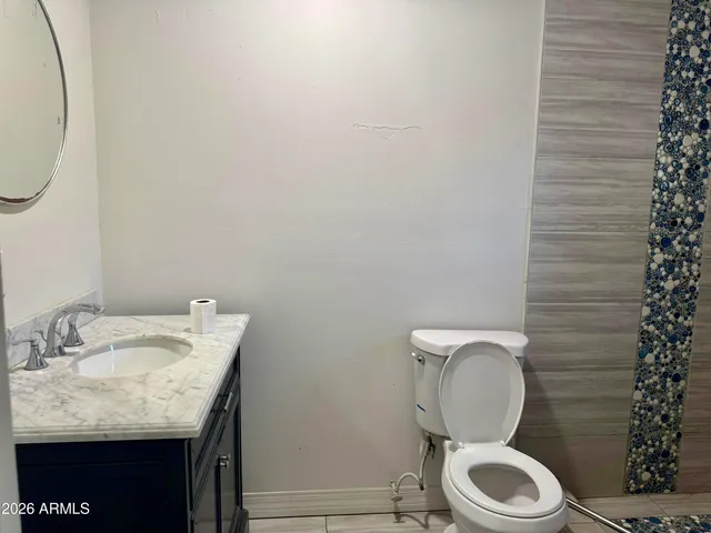 a bathroom with a granite countertop toilet and a sink
