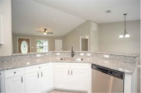 a kitchen with stainless steel appliances kitchen island a stove a sink and a granite counter tops with white cabinets