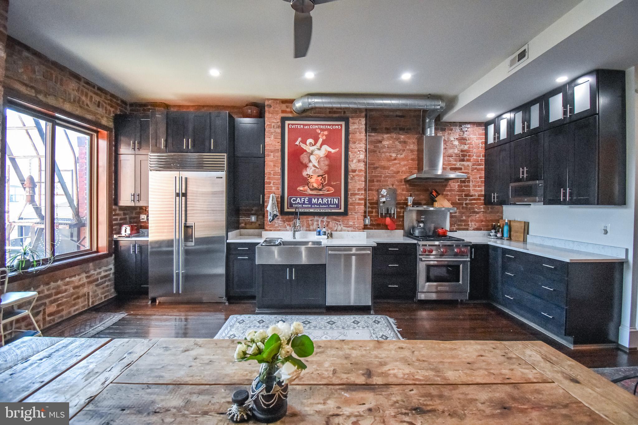 1830 Columbia Road Northwest Washington, DC 20009 - Photo 13 of 46 a large kitchen with kitchen island granite countertop a large window and stainless steel appliances