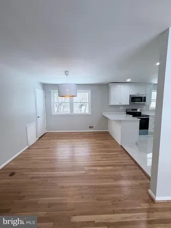 a view of kitchen and empty room with wooden floor