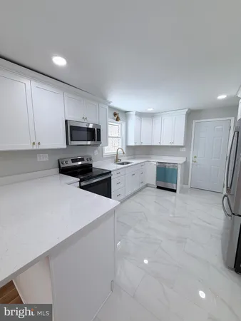 a kitchen with stainless steel appliances a stove a sink a refrigerator a microwave and cabinets