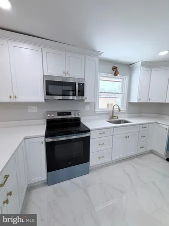 a kitchen with granite countertop white cabinets and stainless steel appliances