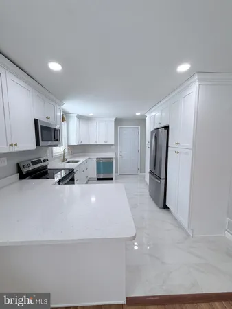a large white kitchen with a refrigerator a stove top oven a sink and dishwasher