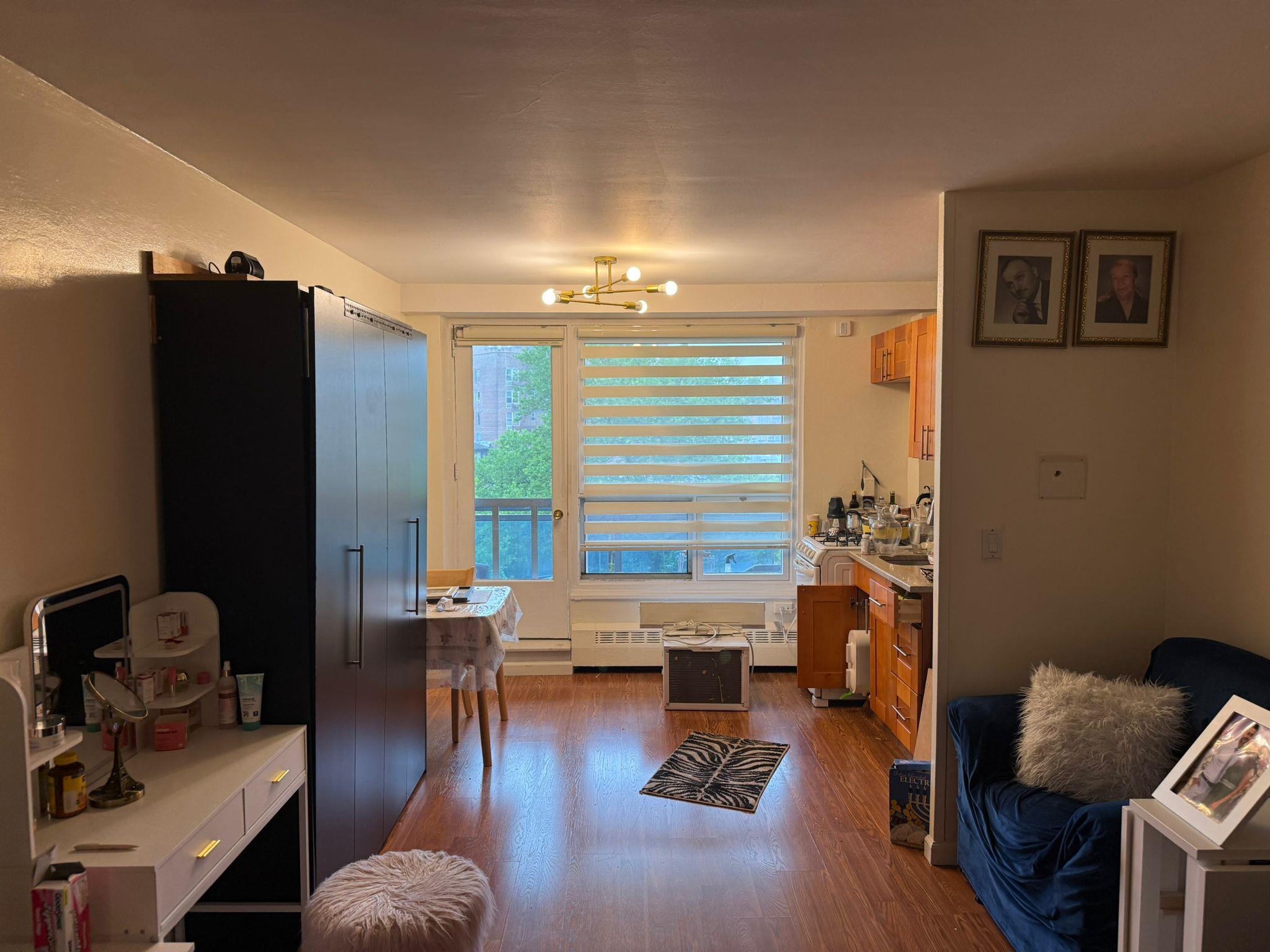 97-37 63rd Road, Unit 5N Queens, NY 11374 - Photo 8 of 17 Living area featuring wood finished floors and a chandelier