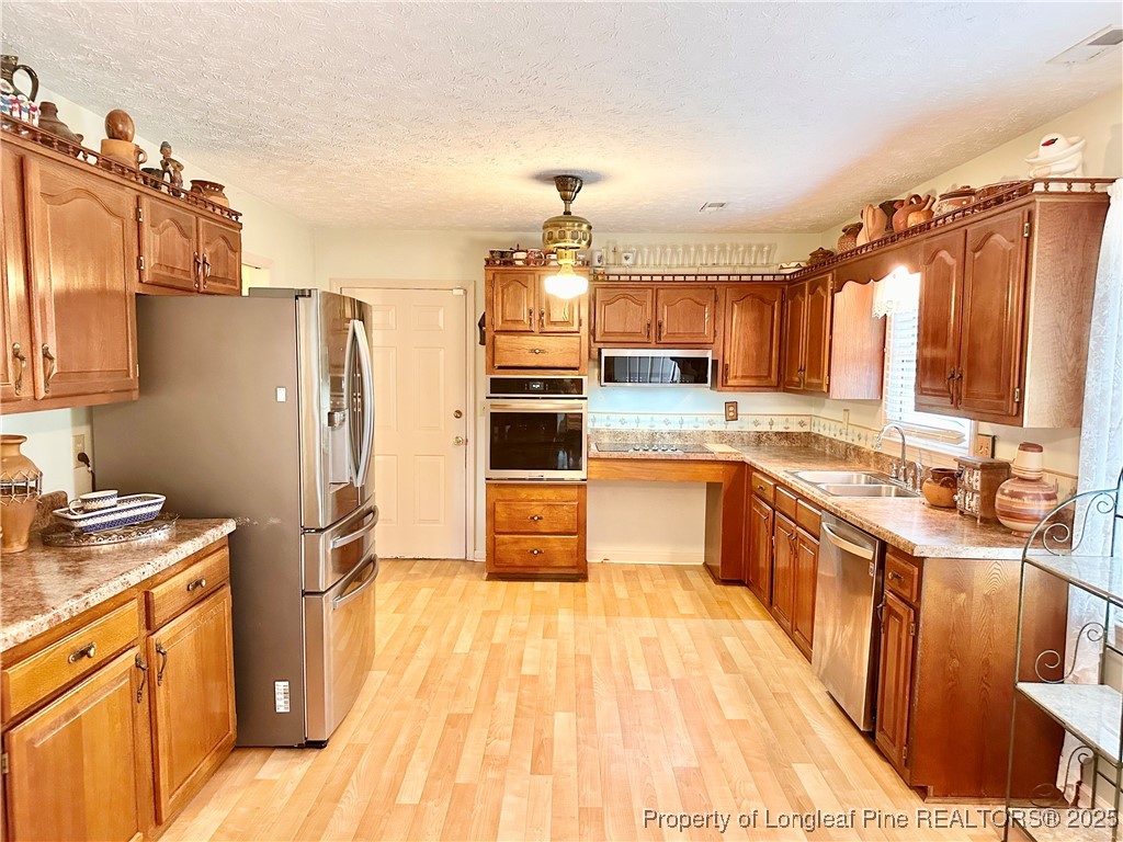 815 Whispering Pines Road Fayetteville, NC 28311 - Photo 18 of 38 a kitchen with stainless steel appliances a refrigerator sink and wooden cabinets