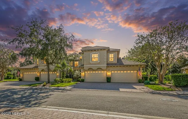 a front view of a house with a garden and tree