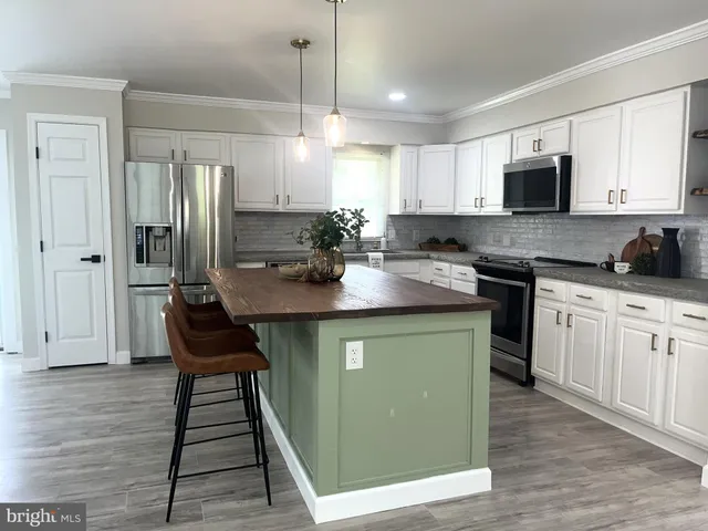 a white kitchen with sink a microwave and cabinets