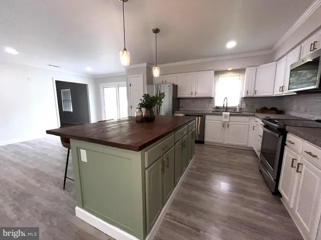 a kitchen with stainless steel appliances a refrigerator a sink a stove a microwave a dining table and chairs