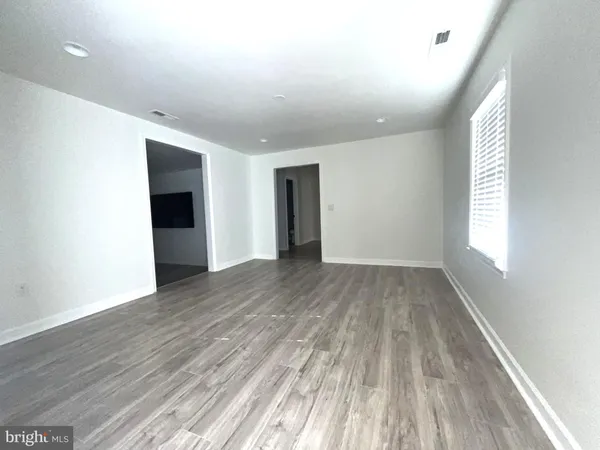 an empty room with a chandelier fan and windows