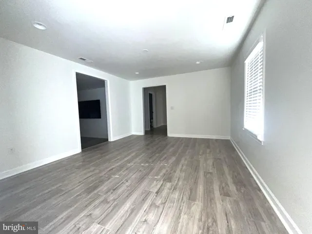 an empty room with a chandelier fan and windows
