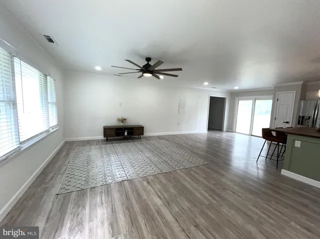 a kitchen with stainless steel appliances kitchen island granite countertop a stove a refrigerator a sink a dining table and chairs with wooden floor