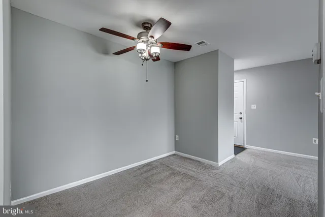 a view of an empty room with a chandelier fan