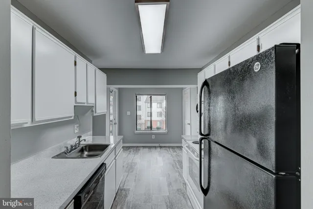 a kitchen with stainless steel appliances granite countertop a refrigerator a sink dishwasher a stove and white countertops with wooden floor